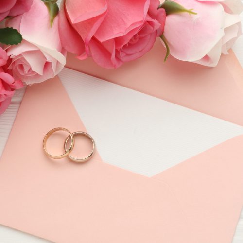 Wedding rings and flowers on white wooden background with space for inscription. High quality photo